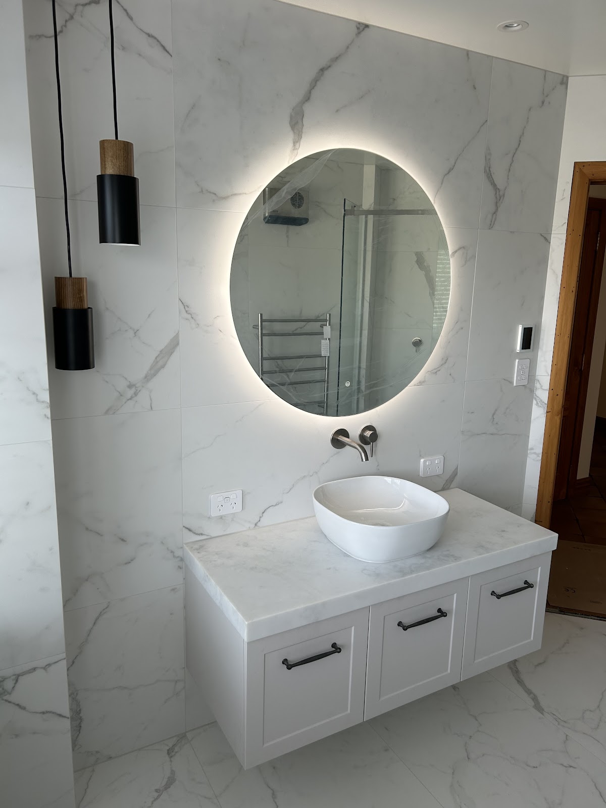 Finished bathroom renovation by Hutt Valley Plumbing with marble tiling and backlit mirror