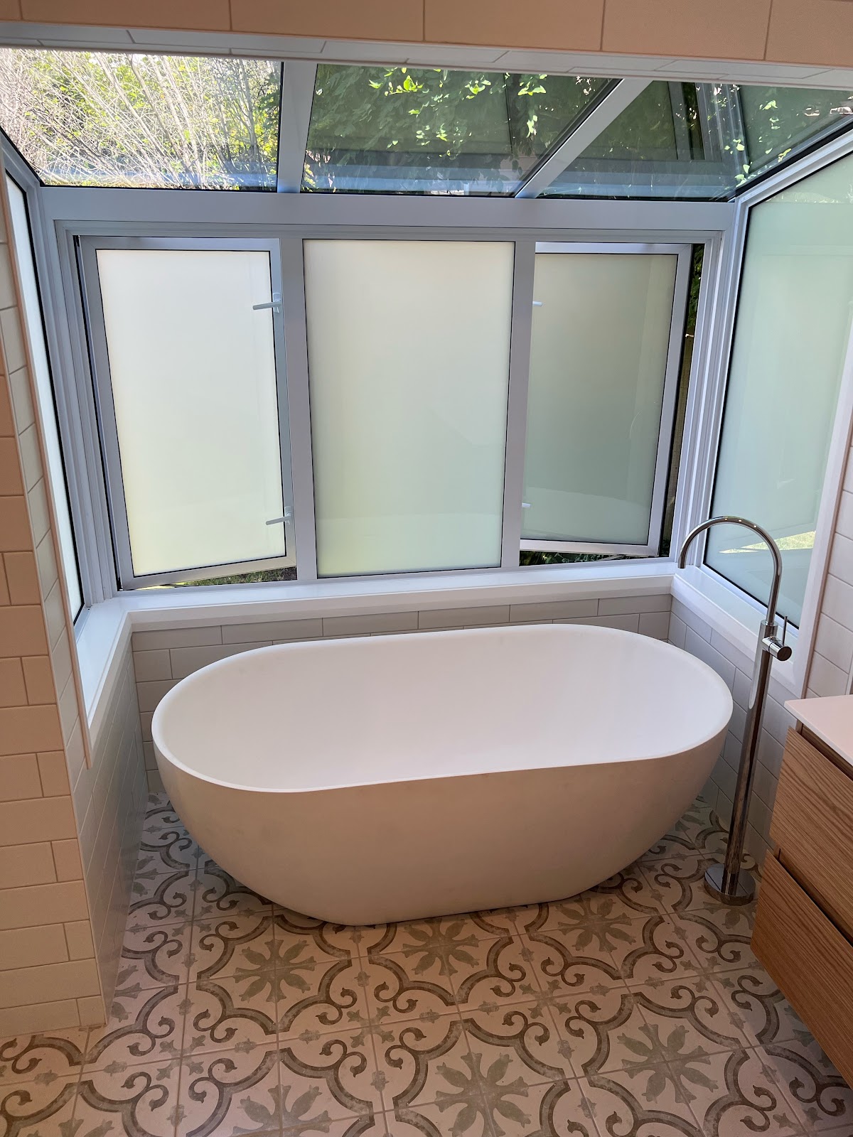 Freestanding bath with floor-mounted filler under glass roof